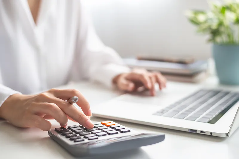 Woman crunching numbers on a calculator and computer